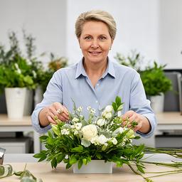 Corporate flower manager preparing a compact office arrangement with green foliage